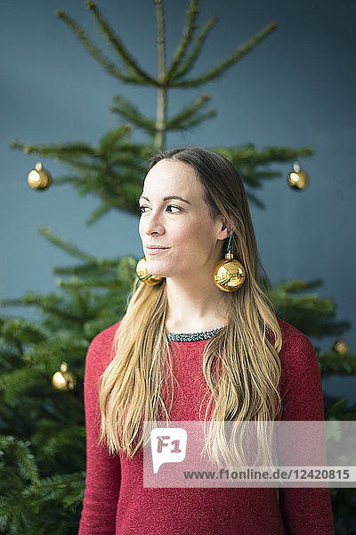 Portrait of woman wearing golden Christmas baubles earrings