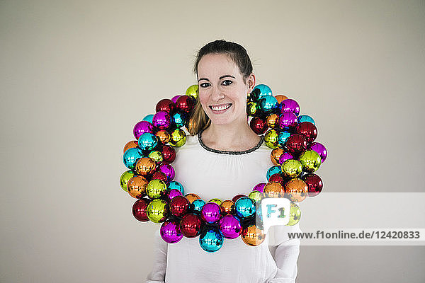 Portrait of smiling woman with colourful Christmas bauble wreath