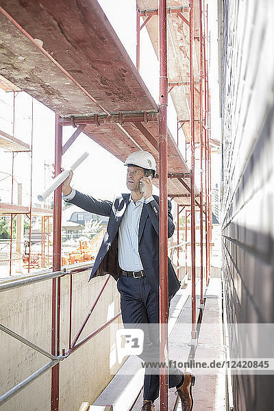 Architect on cell phone on scaffolding on construction site