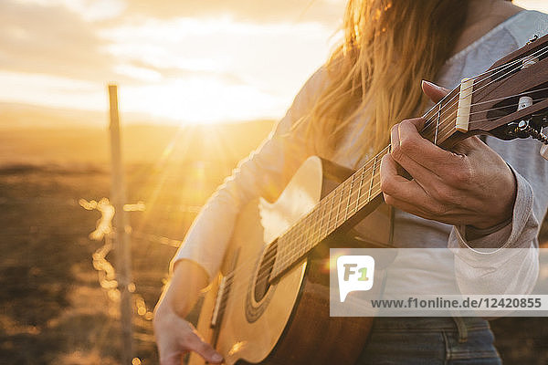 Iceland  woman playing guitar at sunset
