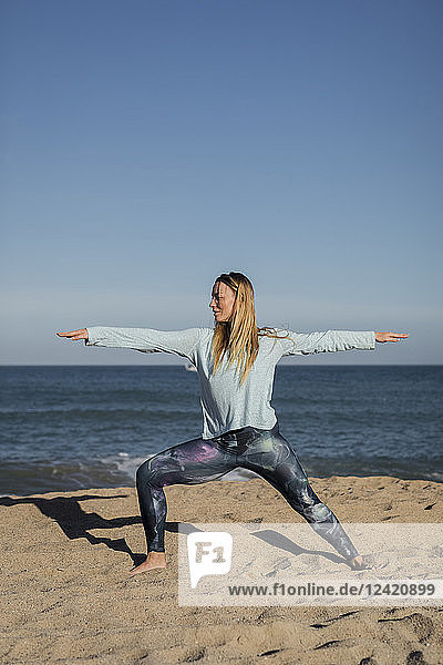 Woman doing yoga on the beach  warrior pose