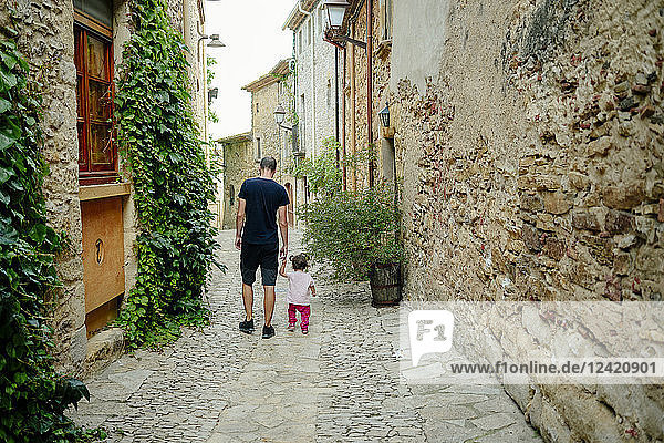 Spain  Catalonia  Peratallada  Medieval Town  Father and daughter walking hand in hand  rear view