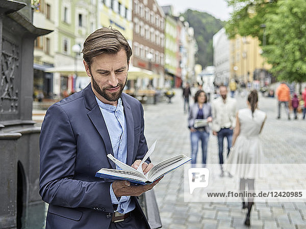 Businessman reading book in the city