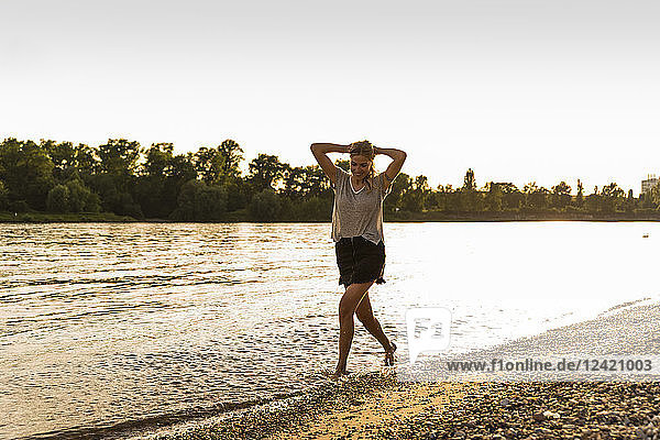 Young woman walking barefoot on riverside