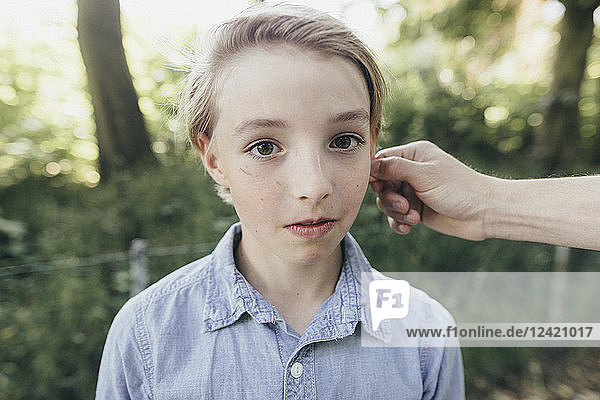 Hand holding ear of a boy