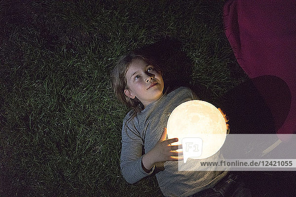 Girl lying on meadow  holding moon