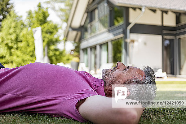 Mature man lying in garden of his home