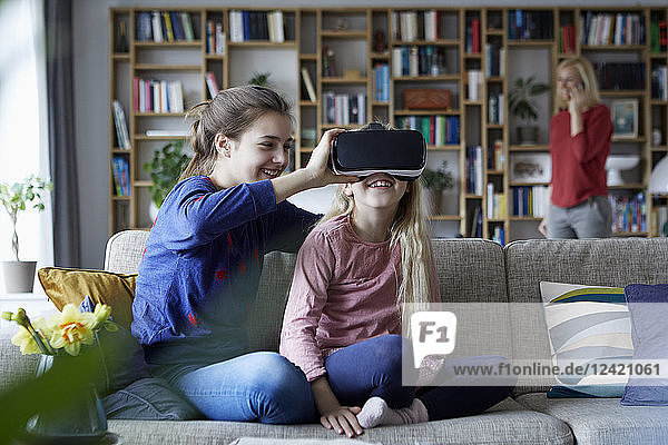Sisters sitting on couch  playing with VR glasses