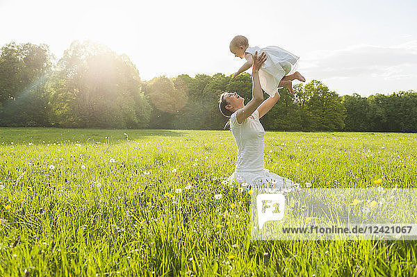 Mother and daughter playing on meadow in summer
