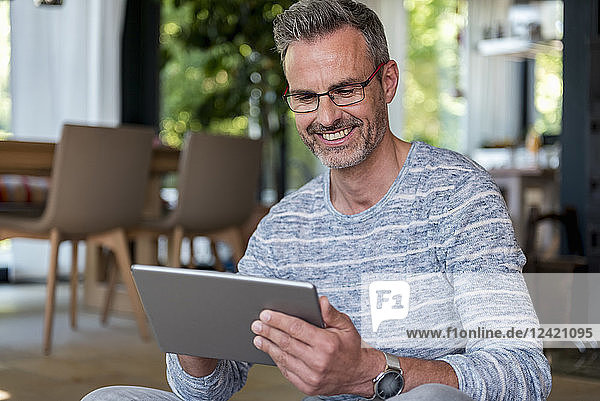 Smiling mature man at home using a tablet