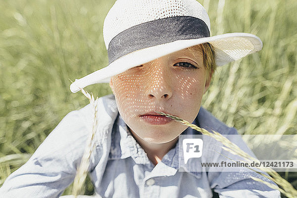 Portrait of boy wearing a hat sitting in field
