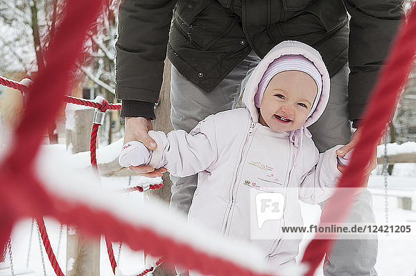 Portrait of smiling baby girl with father on playgroud in winter