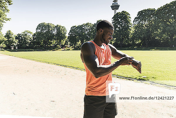 Young athlete in training on sports field taking the time on his smartwatch