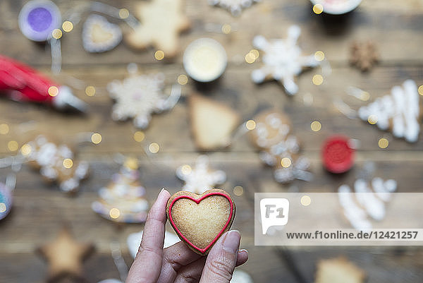 Woman's hand holding heart-shaped gingerbread cookie  close-up