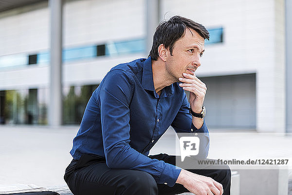 Businessman sitting outdoors thinking