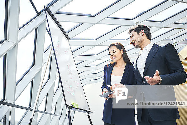 Businessman and businesswoman working with flip chart in office