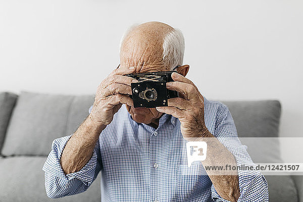 Senior man taking a photo with an old photo camera
