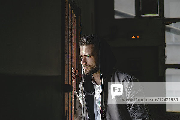 Young man with hood looking out of window