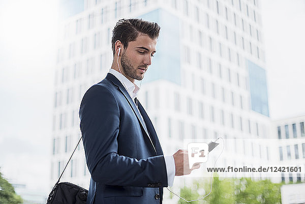Businessman at the window with earbuds and cell phone