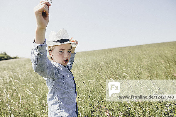 Boy wearing a hat dancing in field