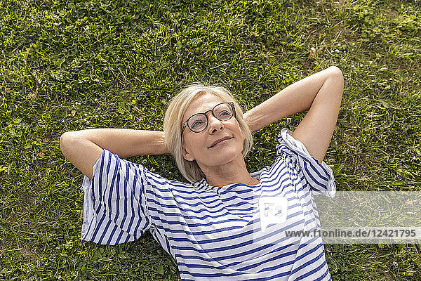 Portrait of smiling senior woman lying in grass