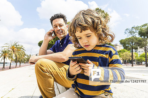 Spain  Barcelona  father and son both with a smartphone
