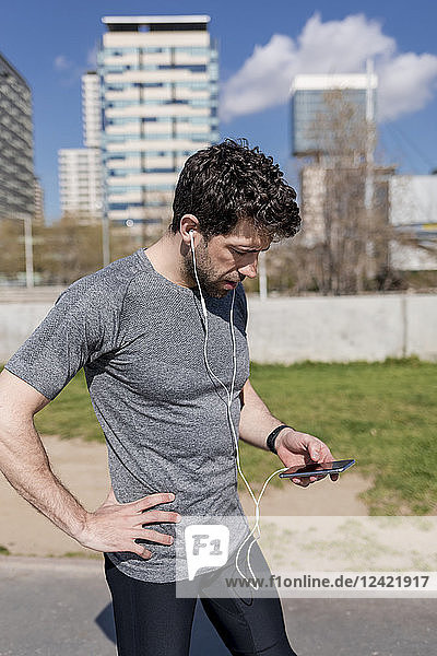 Sportive man with cell phone and earphones in urban area