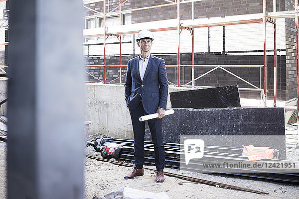 Confident architect wearing hard hat standing on construction site