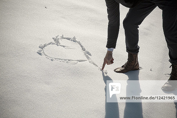 Man painting heart in snow