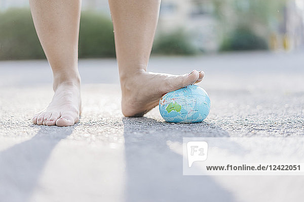 Foot of young woman stepping on globe