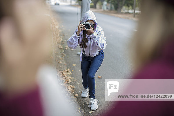 Teenage girl taking a picture of her friends on the street