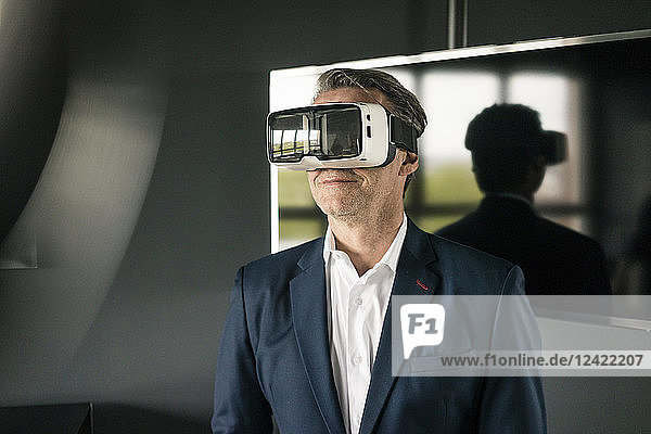Mature businessman wearing VR glasses in office