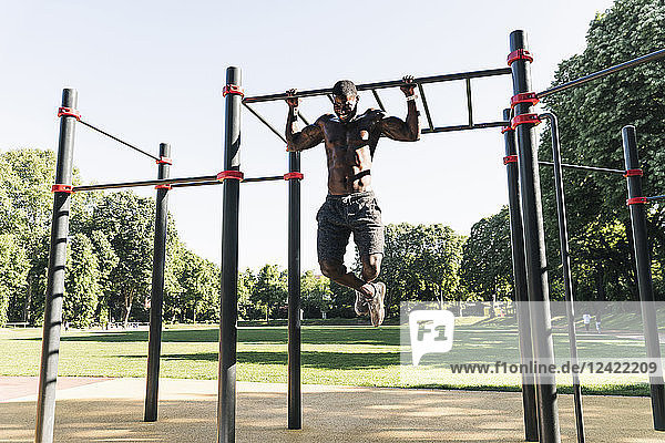 Muscular young man exercising on parcours bars