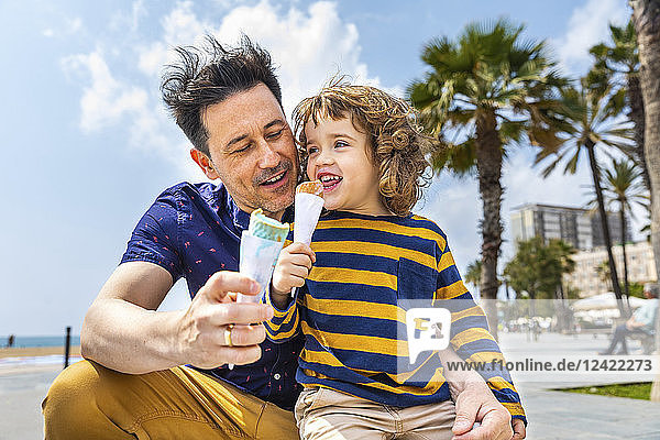 Spain  Barcelona  father and son enjoying an ice cream at seaside