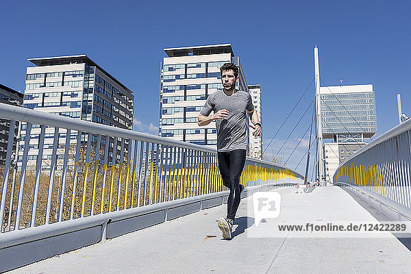 Sportive man runinng on a bridge in the city