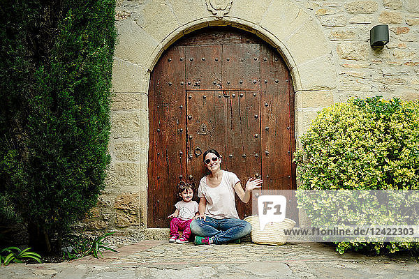 Mother and baby girl sitting at old wooden door