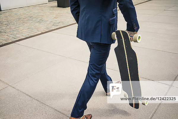 Businessman walking with longboard outdoors