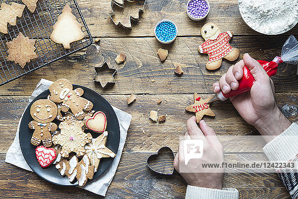 Man's hand decorating Christmas cookie