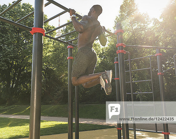 Muscular young man exercising on parcours bars
