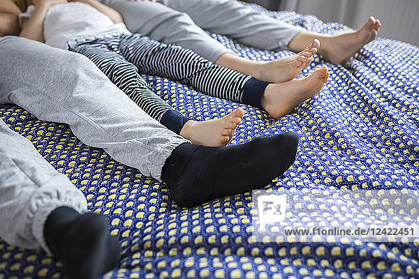 Family of three lying on bed  low section