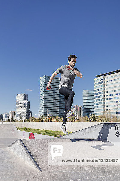 Sportive man jumping in a skatepark in the city