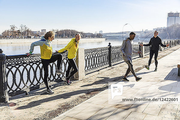 Friends exercising on waterfront promenade in the city