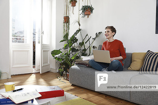 Woman sitting on couch  using laptop