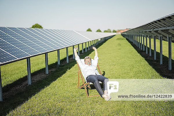 Mature man sitting in sun lounger  solar plant