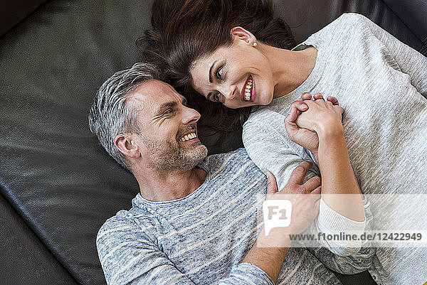 Happy couple lying on couch at home