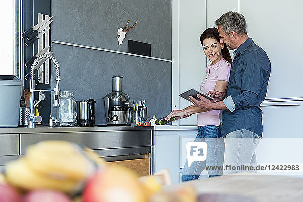 Couple in kitchen at home using a tablet