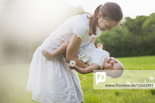 Mother and daughter playing on meadow in summer