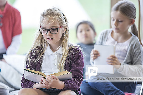 Schoolgirls reading books in school break room