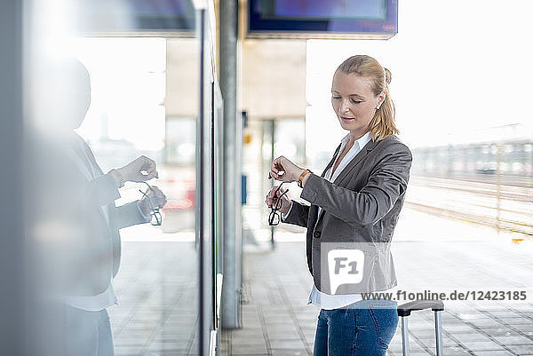 Mature businesswoman standing at platform checking the ime