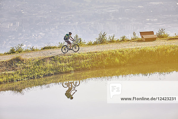 Austria  Tyrol  female mountainbiker at lake in the evening light